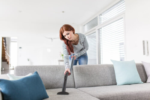 A woman vacuuming a sofa.