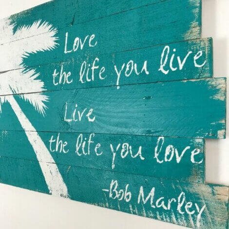 A wood decorative sign with a Bob Marley quote on it