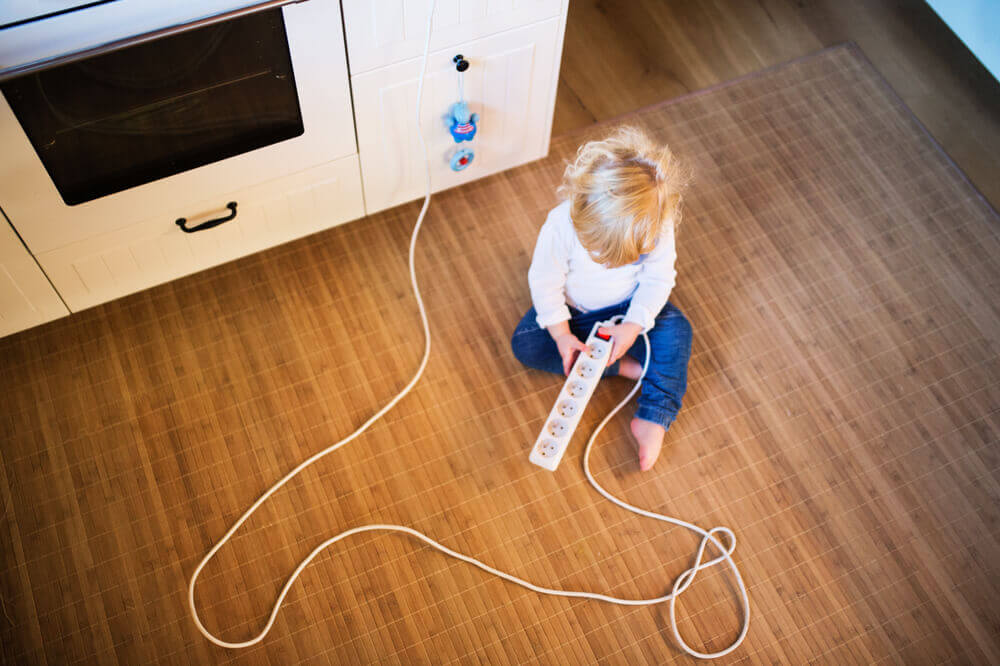 A child playing with a power strip.