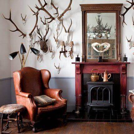 A living room decorated with several pieces of hunting home decor such as antlers and earthy tones