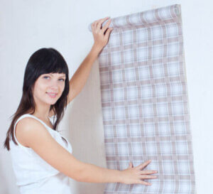 A woman hanging wallpaper.
