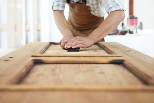 A man who is sanding a piece of furniture