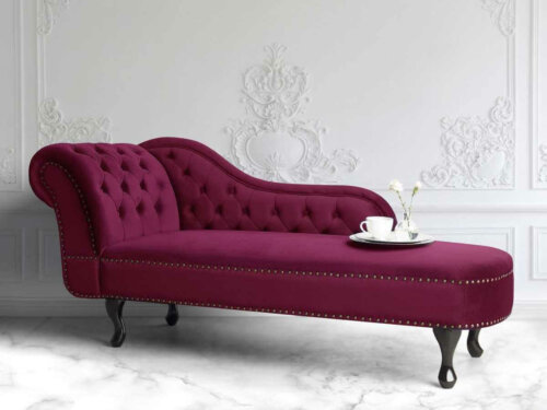 A bright burgundy chaise-longue chair in a white room.