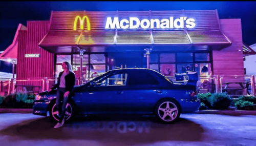 A car parked in front of a restaurant with an iconic logo.