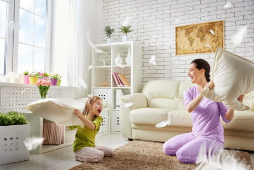 A mother and daughter having a pillow fight.