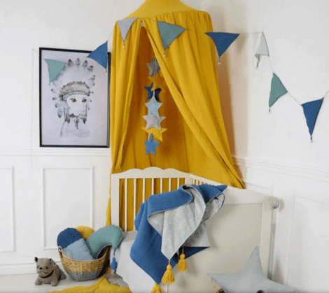 a child's bed with an ochre colored tent above it
