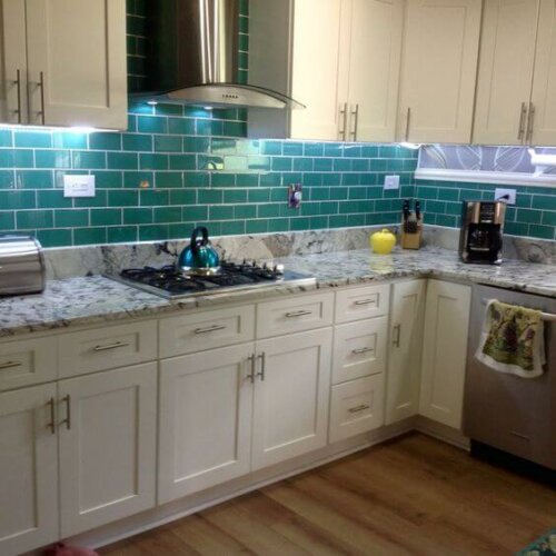 A kitchen with some emerald blue tiles.