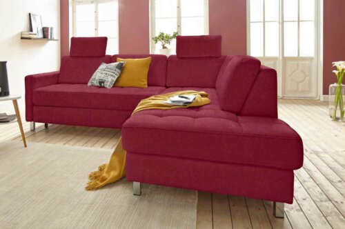 A maroon sofa with some pillows and a throw.