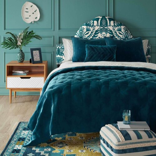 An emerald blue bed in a bedroom.