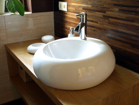 A white round sink on a brown vanity to update your bathroom. 
