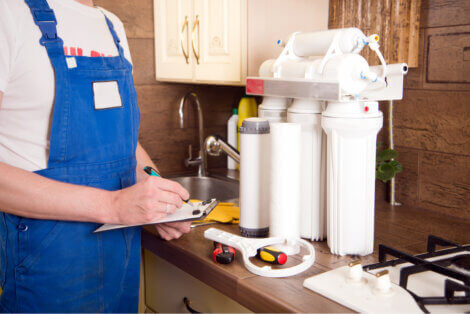 Someone in a kitchen changing filters on a water filtration system