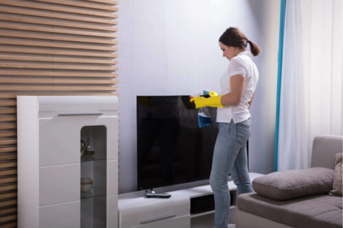 A woman cleaning a TV screen.