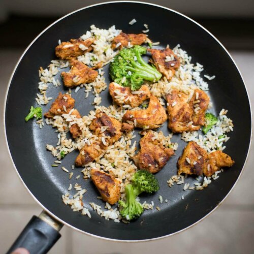 A pan with some chicken, rice and broccoli.