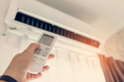 A person changing the temperature of an air conditioner.