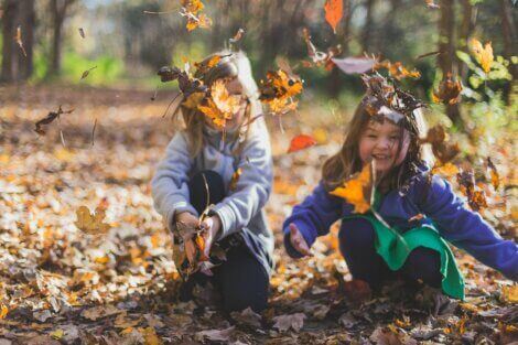 Children gathering up leaves in a yard