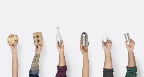 Four hands holding up recyclable items for a sustainable house