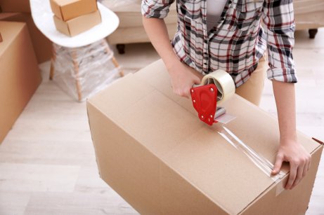 A person taping up a cardboard box, organization to show distadning