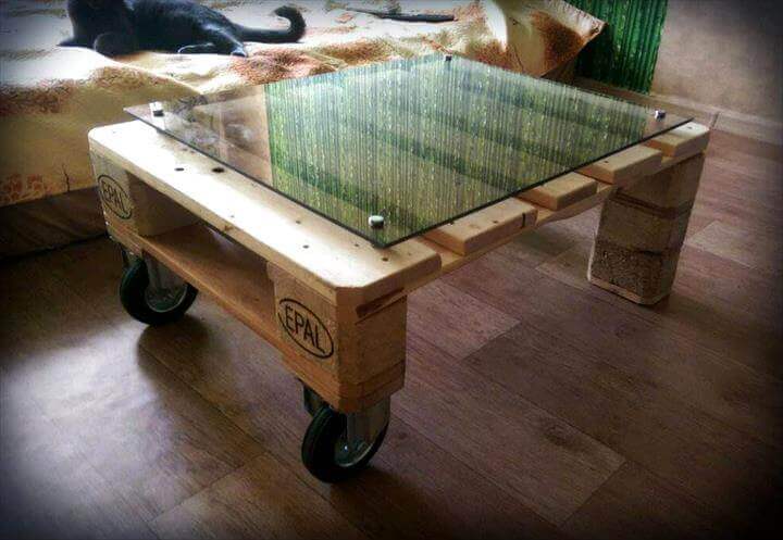 Table made of wooden pallets, with glass pane on top.