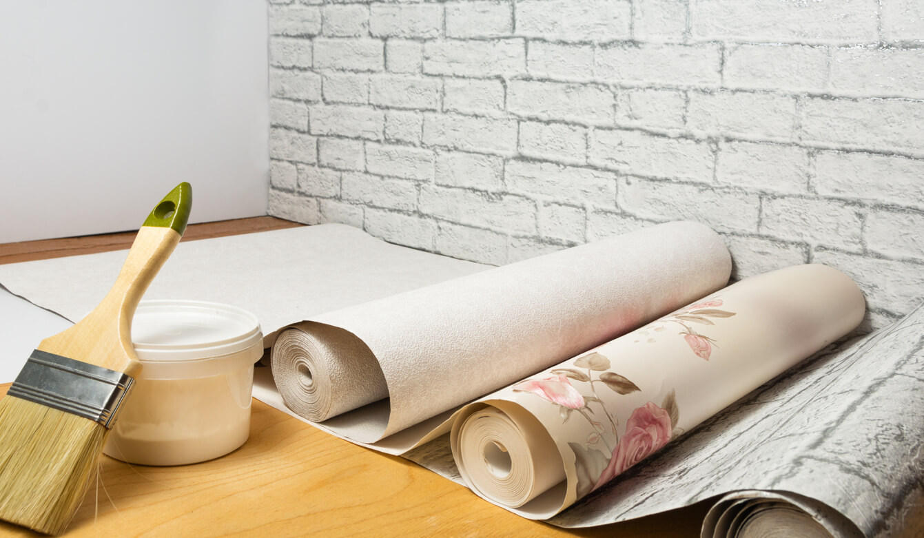 Multicolored rolls of wallpaper, brush, glue, and paint are ready for renovating your apartment. Do-it-yourself apartment renovation concept.