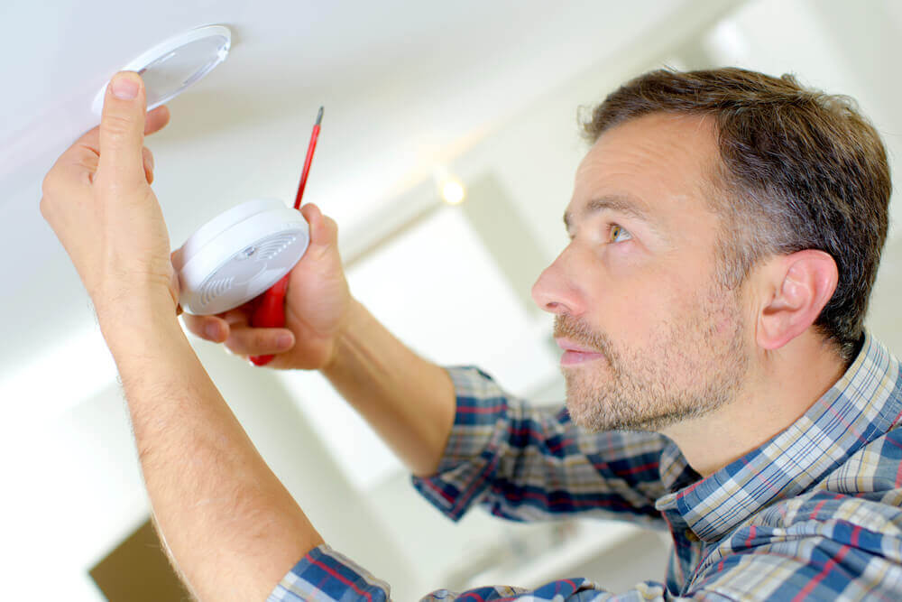 A man installing a fire detector.