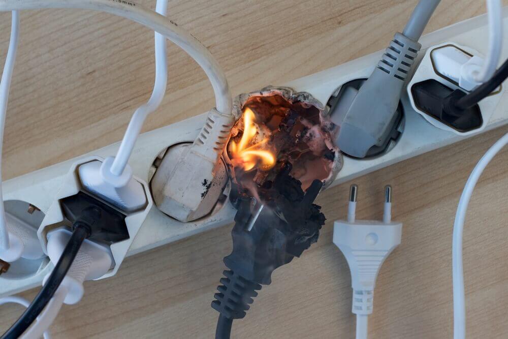 An overloaded power strip that's overloaded and has short circuited, causing a fire.