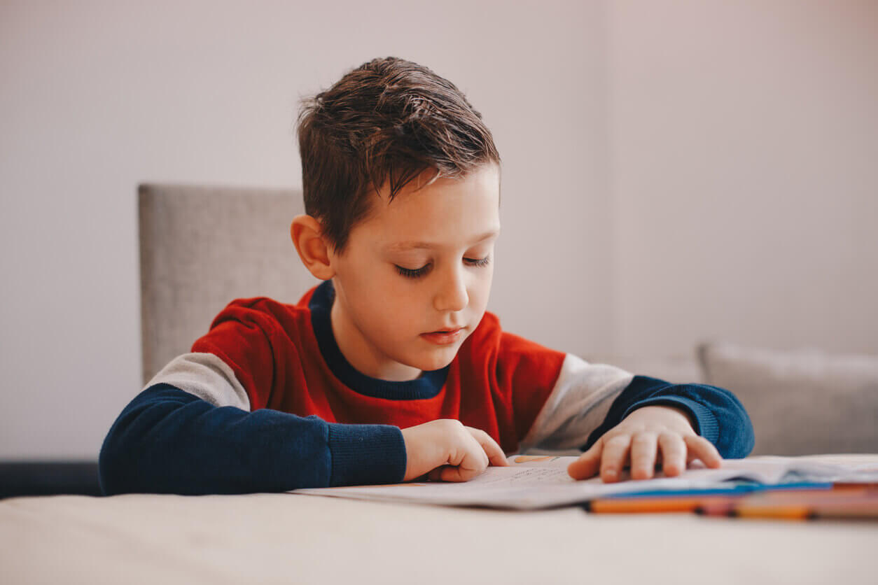 A young boy reading in a neutral-colored study room.